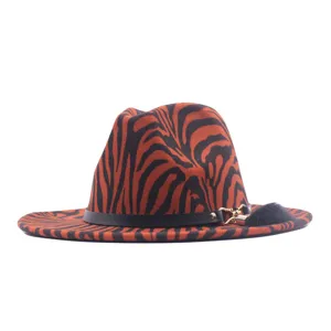 Orange and black animal print fedora hat featuring a black leather belt and fluffy charm.