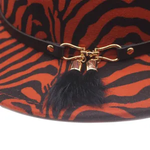 Close-up detail of stylish autumn winter fedora hat with animal print, leather strap and tassels.