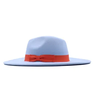 Detailansicht eines hellblauen Schlapphutes aus Wolle mit einer leuchtend orangefarbenen Schleife.