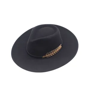 Nahaufnahme Detail des schwarzen Woll Fedora Hutes mit goldenem Blatt Zweig Accessoire.