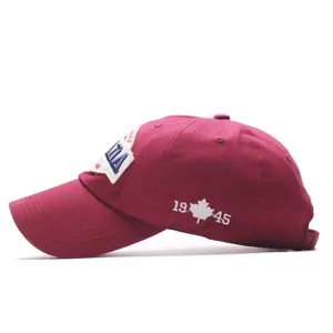 Burgundy baseball cap side detail, classic embroidered logo and maple leaf, stylish cotton hat.