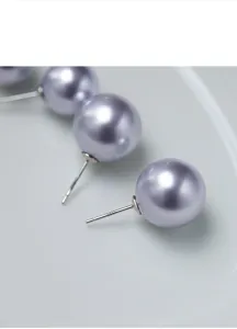 Détail de boucles d'oreilles perles lavande, tige en argent S925, bijoux élégants et ronds.