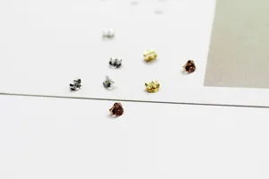 Nahaufnahme von verschiedenen silbernen, goldenen und roségoldenen Schmetterling-Ohrringverschlüssen.