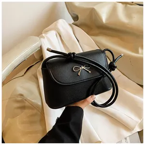Black leather underarm shoulder bag detail with metal bow decor and chic strap design.