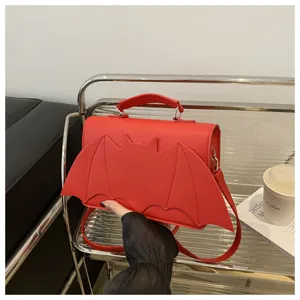 Detailed view of the red bat wing crossbody bag, showcasing the unique flap design and texture.