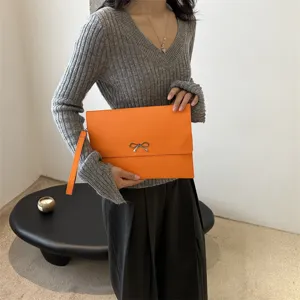 Mujer moda naranja sobre embrague bolso minimalista pulsera elegante chic accesorio