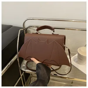 Detailed shot of trendy brown bat wing handbag, featuring unique design and shoulder strap.