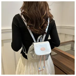 Vue détaillée d'un petit sac à dos argenté métallisé, style rétro mignon sac quotidien.