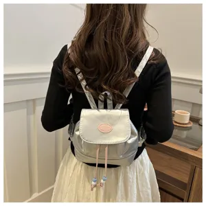 Vue détaillée du mini sac à dos métallisé élégant avec cordon rose et breloque de perles.