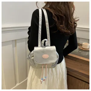 Vue détaillée d'un élégant mini sac à dos argenté avec des perles roses et un cordon.