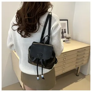 Vue détaillée d'un mini sac à dos noir en cuir PU avec cordon de serrage et bretelles fines.