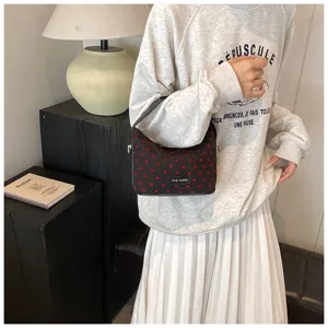 Detailed view of the cute black shoulder bag with red heart patterns for casual daily wear.