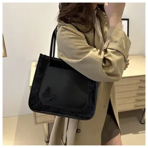 Vue détaillée d'un sac cabas noir avec des empiècements en velours et un papillon porté par le mod.