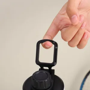 Gros plan sur la poignée pliante portable et le couvercle d'une gourde de sport noire.