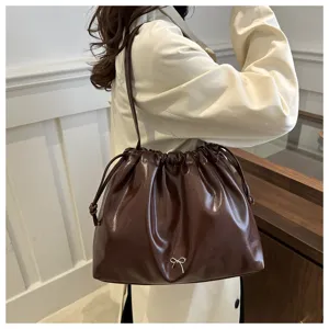 Stylish women's brown soft leather bucket shoulder bag with drawstring and cute bow detail.