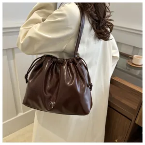 Detail shot of a dark brown soft leather shoulder bucket bag with elegant bow decoration.