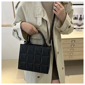 Detailed view of women's trendy black quilted cross-body bag with stylish geometric pattern.