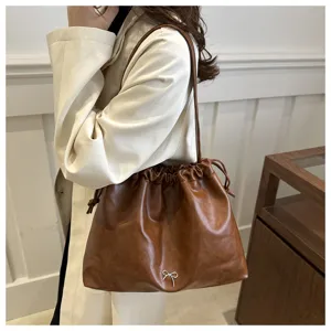 Detail shot of the brown soft leather shoulder bucket bag with drawstring and cute bow accent.