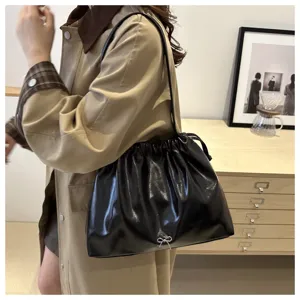 Elegant black soft leather shoulder bag with chic drawstring and bow detail for women commuting.