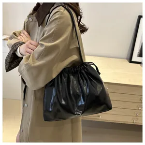 Detail view of black soft leather shoulder bag with drawstring closure and cute bow accent.