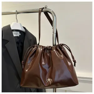 Dark brown glossy leather shoulder bucket bag with stylish drawstring and cute bow detail.