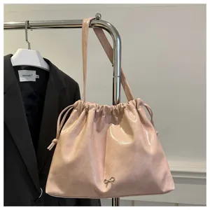 Pink shiny soft leather shoulder bucket bag with drawstring closure and chic bow detail.