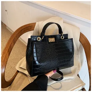 Vista dettagliata della elegante borsa a tracolla con motivo coccodrillo nero e serratura in metallo.