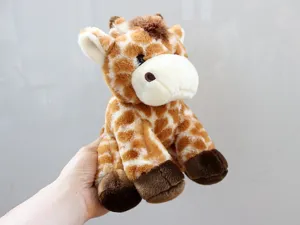 Vue détaillée de la jolie peluche girafe assise, présentant une texture de fourrure douce et mignonne.