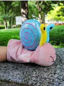Cute plush snail hand puppet toy, soft interactive animal doll for kids, detail view outdoor.