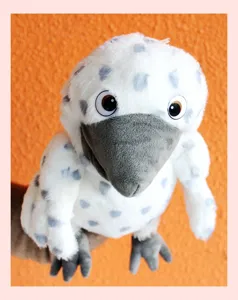 Plush bird hand puppet detail shot, soft white fabric with grey spots and big beak.