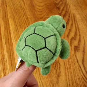Green turtle finger puppet plush toy close-up detail shot, soft fabric, cute animal design.
