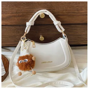 Vue détaillée du sac hobo croissant blanc en cuir doux avec son pendentif peluche.
