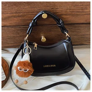 Sac bandoulière noir en croissant avec poignée nouée, quincaillerie dorée et peluche.