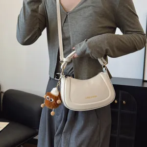 Élégant sac bandoulière croissant blanc avec joli pendentif peluche, style chic.