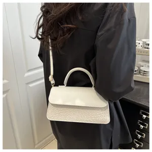 Detail view of the white retro crossbody bag, showing the woven embossed texture and handle.