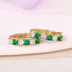 Detailed view of French style gold-plated U-shaped huggie hoop earrings with green and clear zircon.