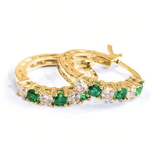 Close-up of gold-plated U-shaped hoop earrings with green and clear zircon stones.
