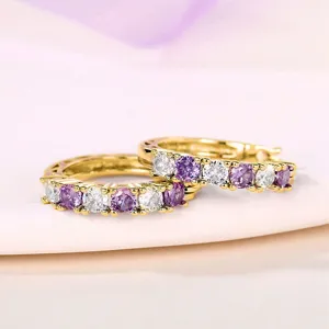Close-up of gold-plated hoop earrings with alternating purple and white cubic zirconia stones.