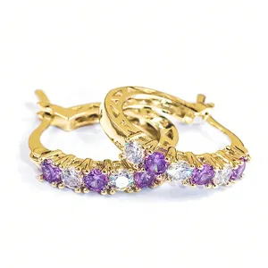 Detail shot of stylish gold-tone U-shaped hoop earrings paved with purple and white cubic zirconia stones.