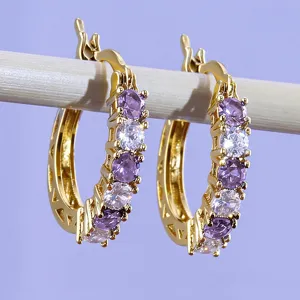 Gold hoop earrings detail shot showcasing purple and clear cubic zirconia stones and metallic shine.