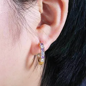 Close-up detail of gold-plated U-shaped hoop earrings featuring alternating purple and clear zirconia stones.