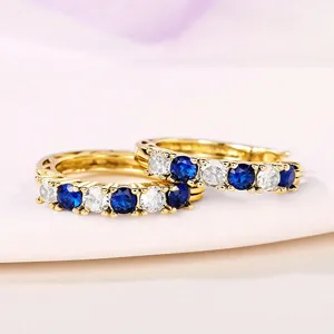 Detail view of fashion U-shaped gold hoop earrings with sparkling blue and white zircon stones.