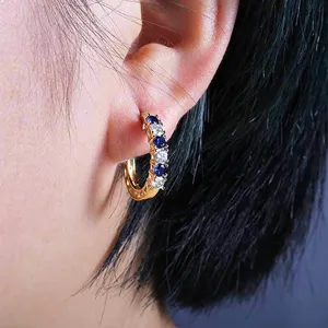 Close-up view of French style gold-plated hoop earrings inlaid with blue and white cubic zirconia.