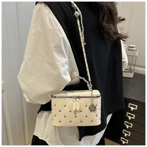 Détail de sac bandoulière matelassé avec motif losange, rivets chics et charm fleur.