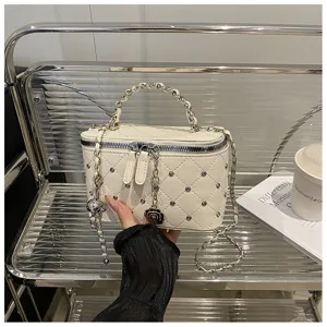 Vue détaillée du sac bandoulière matelassé blanc avec des rivets chics et une poignée chaîne.
