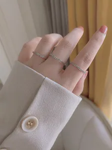 Dettaglio di anelli impilabili delicati in argento, gioiello da dito minimalista ed elegante.