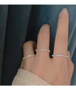 Primer plano detallado de anillos brillantes finos y apilables de plata en los dedos.