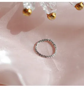 Primo piano dettagliato di un anello morbido in argento sterling scintillante su raso rosa.