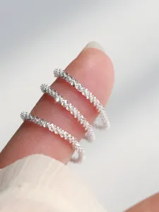 Primer plano detallado de anillos apilados de plata esterlina 925 con textura brillante.