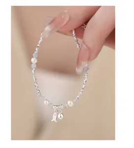 Nahaufnahme Detail eines Sterlingsilber Armbands mit Perlen, blauen Perlen und Fisch.